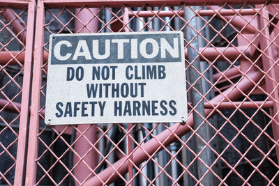 Close-up of warning sign on chainlink fence