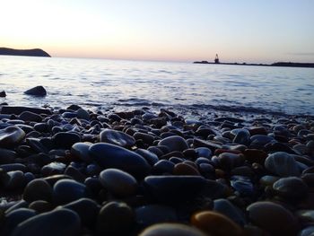 Close-up of pebbles at beach against sky during sunset