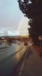 Cars on road against rainbow in sky