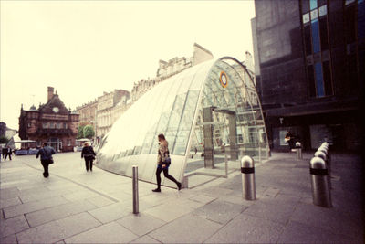 People walking on street amidst buildings in city