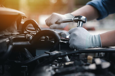 Cropped hand of mechanic repairing car