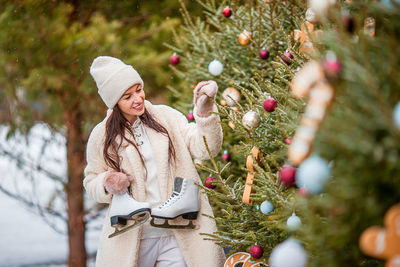 Portrait of young woman standing by christmas tree