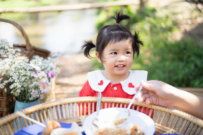 Cropped hand of mother feeding girl while sitting at park