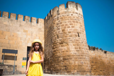 Portrait of woman standing against building