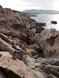 Rock formation on sea shore against sky