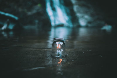 Close-up of illuminated candle with glass jar in water