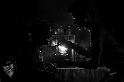 Boy and mother by illuminated gas lantern in darkroom