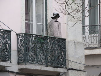 Bird perching on statue against building