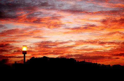 Silhouette trees against dramatic sky during sunset