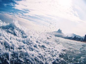 Close-up of sea waves against cloudy sky at sunset