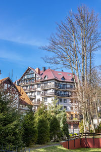 View of the swiss-style house residential complex behind green trees and fir trees. 