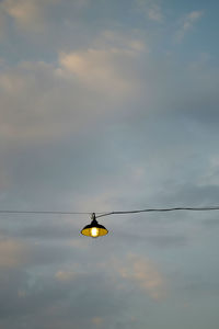 Low angle view of helicopter hanging on cable against sky