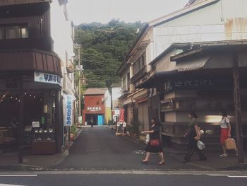 People walking on street amidst buildings in city