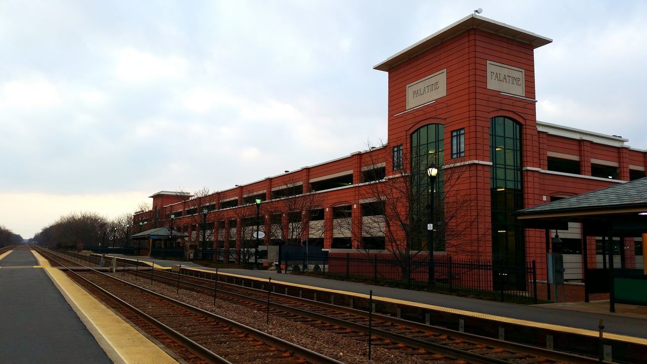 architecture, railroad track, building exterior, built structure, rail transportation, public transportation, transportation, sky, railroad station, train - vehicle, railroad station platform, cloud - sky, city, train, travel, day, passenger train, outdoors, cloud, no people