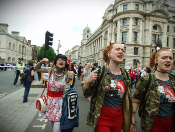 Happy friends standing against buildings in city