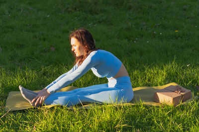 Side view of woman sitting on field