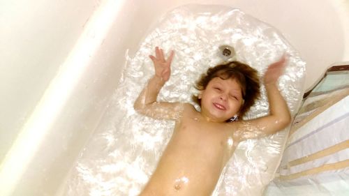 Smiling young woman with arms raised in bathroom