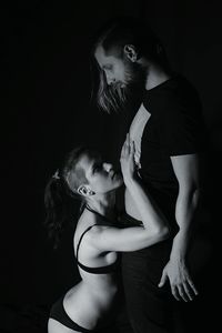 Side view of sensuous woman with boyfriend against black background