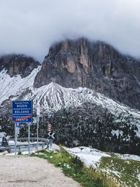 Snow covered road by mountains against sky