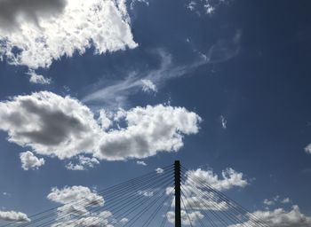 Low angle view of suspension bridge against cloudy sky