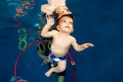 Parent with baby boy swimming in pool