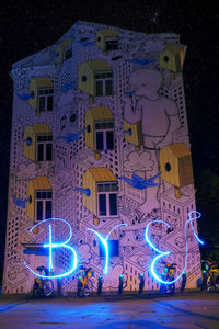 Illuminated street light against building at night