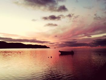 Silhouette boats in calm sea at sunset