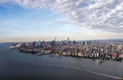 City at waterfront against cloudy sky