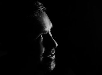 Close-up of man looking away against black background