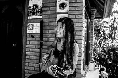 Smiling young woman playing guitar