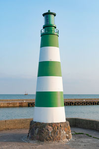 Lighthouse by sea against clear sky