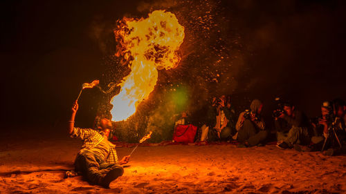 Man showing fire stunt by photographers on desert at night