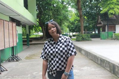 Portrait of young woman standing against trees