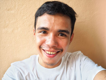 Portrait of smiling young man against wall