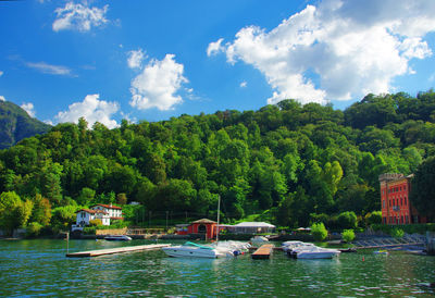 Boats moored at lake como by mountain against sky