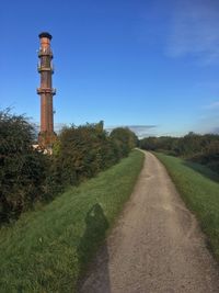 Road leading to lighthouse against clear blue sky