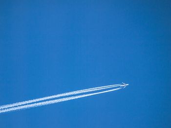 Low angle view of airplane against clear blue sky