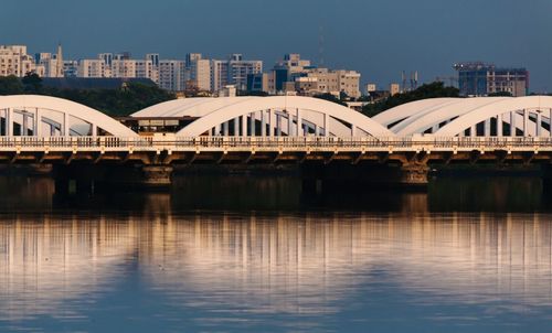 Bridge over river in city against sky