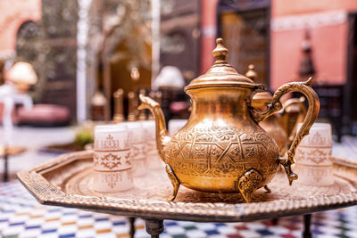 Traditional ornate copper teapot with glasses on table