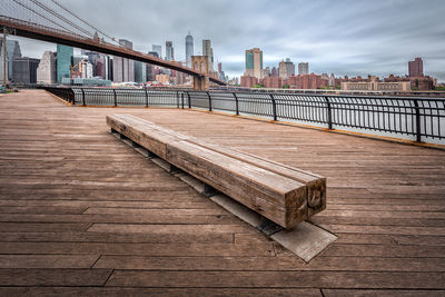 Wooden seat on promenade in city