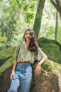 Young woman smiling while standing against trees