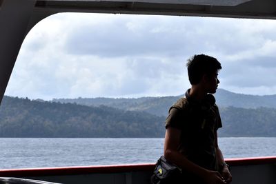 Man sailing in ferry against sky