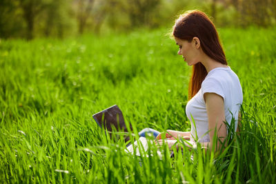 Side view of young woman sitting on field