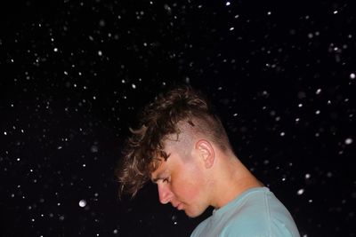 Side view of man standing against sky at night