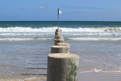 Wooden posts on beach against sky