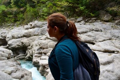 Side view of backpack woman standing on rock formation