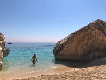 Rear view of woman on shore at beach against sky