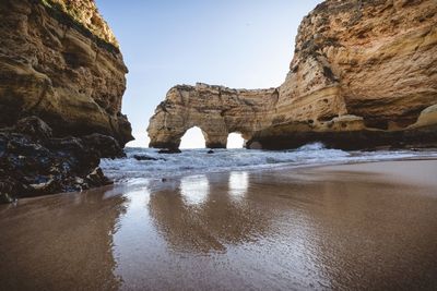 Rock formations on beach against sky