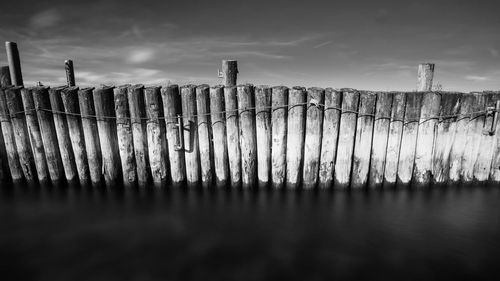 Wooden posts on fence against sky