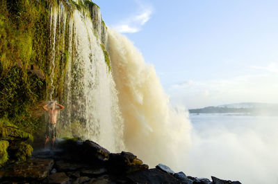 Panoramic view of waves splashing on rocks against sky